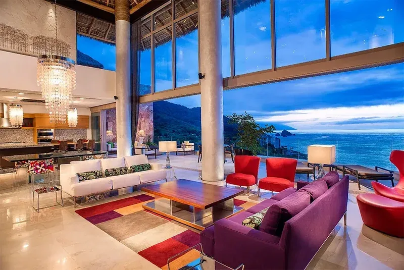 Double-height living room beneath the palapa roof with walls of glass facing the bay
